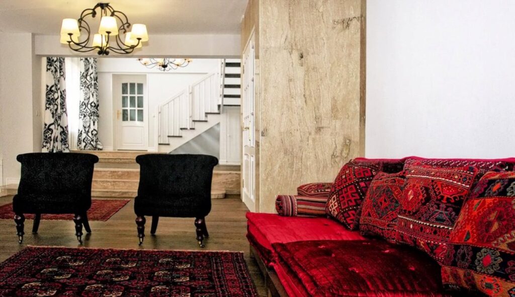 Holul de intrare al casei de vacanţă de la Snagov, cu canapea, fotolii clasice negre şi covor persan