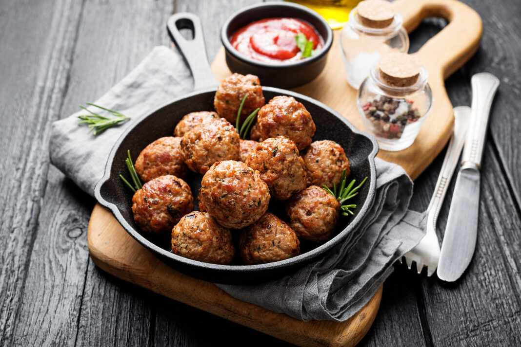 Meatballs served with tomato sauce in frying pan .