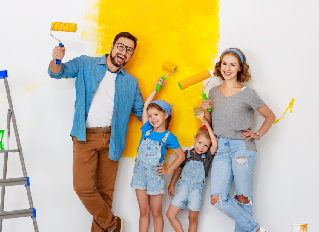 Repair in apartment. Happy family mother, father and children   paints wall