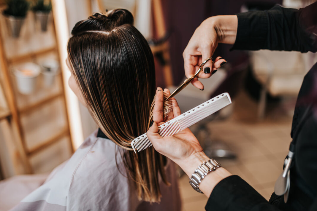 Beautiful young woman getting her haircut by a hairstylist at a