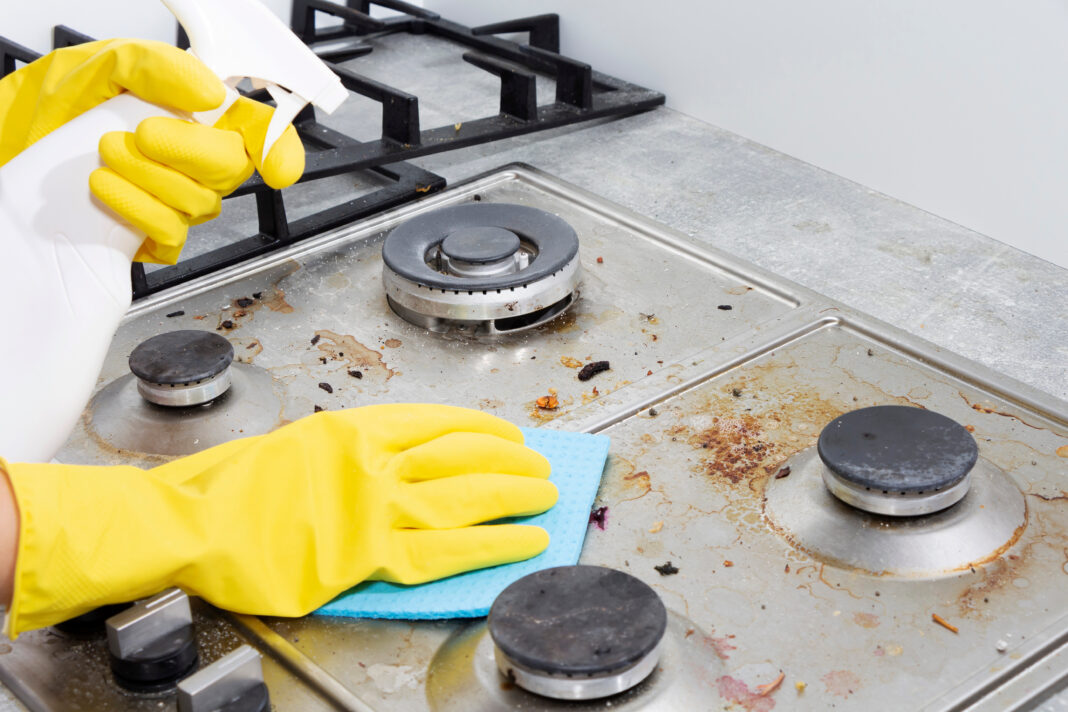 Cleaning a gas stove with kitchen utensils, household concepts, or hygiene and cleaning.