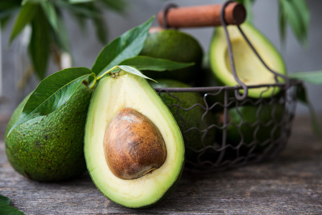 Fresh green avocado on wooden background. Selective focus. Horizontal orientation.