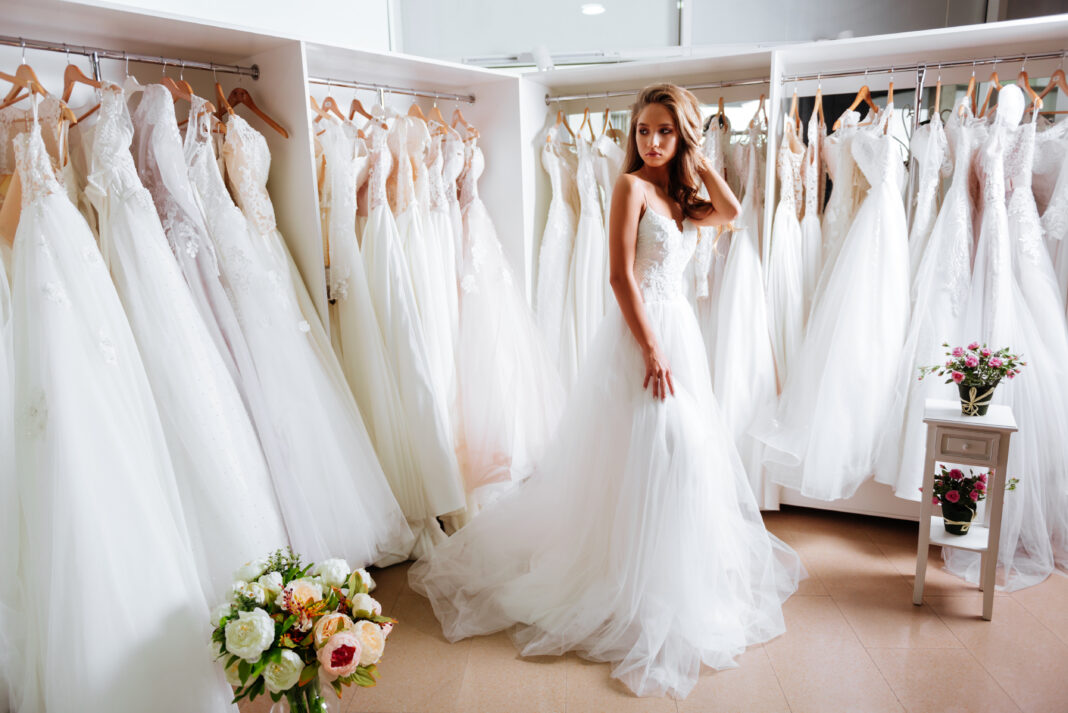 Back view of a young woman in wedding dress looking at bridal gowns