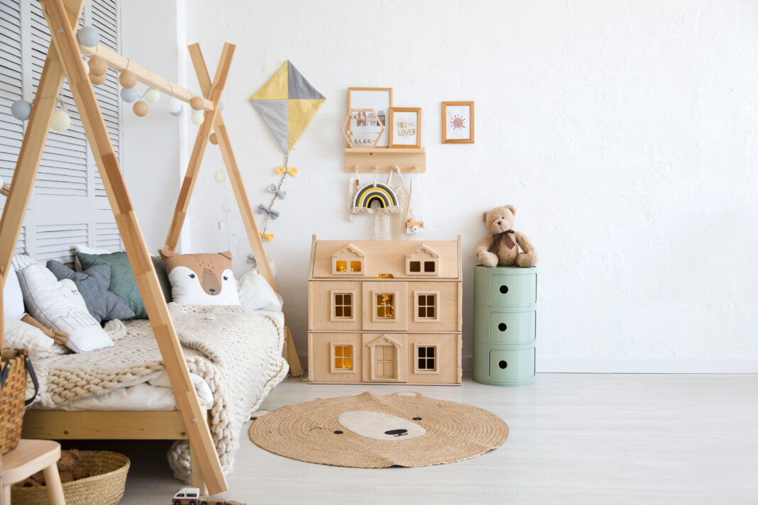 Stylish baby room with toys, wooden bed and mock up poster frame. Cute home decor. Scandinavian interior of a children's room.