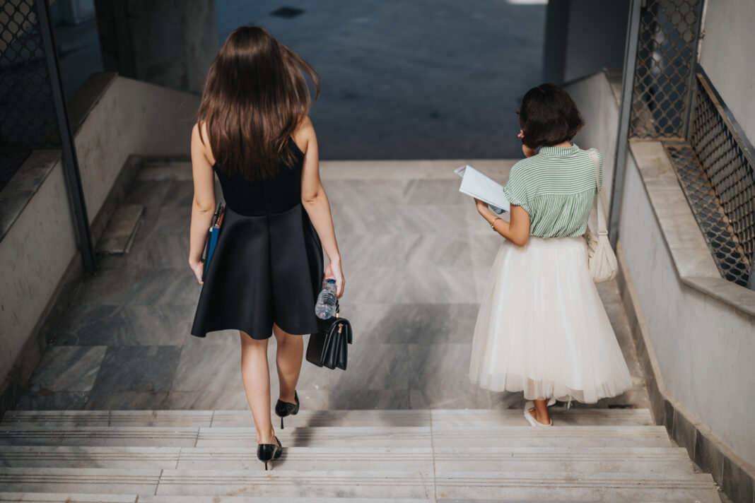 Women walking down stairs in urban setting carrying documents and bags