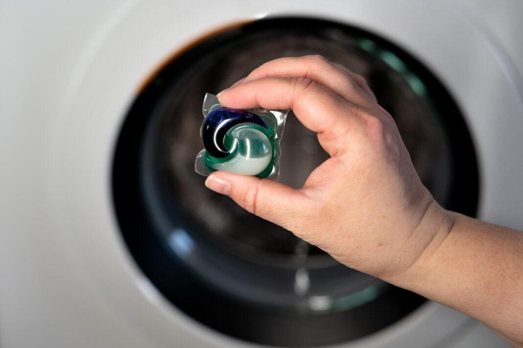 Hand holding detergent. Concept: laundry and dry cleaning services that ensure cleanliness and garment care.