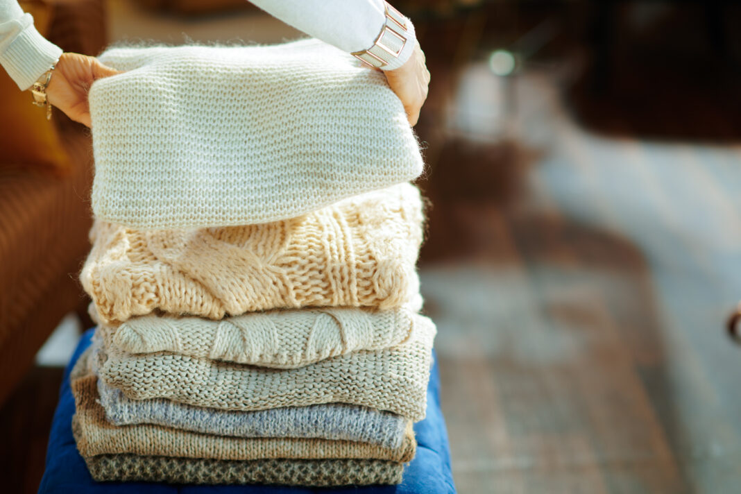 Closeup on elegant woman prepare sweaters pile for storage